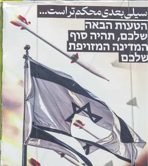  ?? ?? A banner depicting missiles and drones flying past a torn Israeli flag, with text in Persian reading ‘the next slap will be harder’ and in Hebrew ‘your next mistake will be the end of your fake state’, hangs on the facade of a building in Palestine Square in Tehran