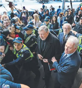  ?? Picture: MARK STEWART ?? Cardinal George Pell (centre) is surrounded by a ring of police officers as he arrives at Melbourne Magistrate­s Court amid chaotic scenes yesterday.