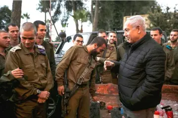  ??  ?? Netanyahu holds a hot drink while being accompanie­d by Major General Yoel Strick (left), commander of the Israeli army’s northern command, as he meets with soldiers in the northern town of Safed. — AFP photo