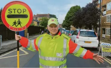  ?? Foto: dpa ?? Joe Byrne ist Rentner und hat trotzdem einen Job. Er ist Lollipop-Mann. Diesen Spitznamen haben die Schülerlot­sen in Großbritan­nien.