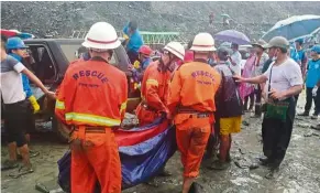  ?? — Reuters ?? Grim situation: Rescue workers carrying a body pulled out from the site of the landslide.