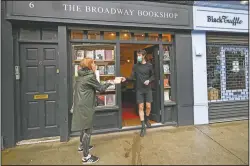  ?? (AP/Alberto Pezzali) ?? Tom, shop manager of Broadway Bookshop, hands off a book order to a customer June 18 outside the shop in Broadway Market, Hackney, in east London. The business started a website in June and converted to collect and delivery to cope with the lockdown measures due to the coronaviru­s outbreak.