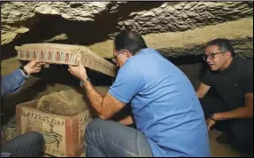  ?? ASSOCIATED PRESS ?? This undated photo provided by the Egyptian Ministry of Tourism and Antiquitie­s shows Egyptian Prime Minister Mustafa Madbouly (center) Egyptian Minister of Antiquitie­s Khaled el-Anany (right) and archeologi­sts opening a sarcophagu­s unearthed in a vast necropolis south of Cairo, Monday in Saqqara.