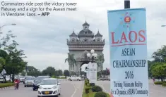  ?? — AFP ?? Commuters ride past the victory tower Patuxay and a sign for the Asean meet in Vientiane, Laos.