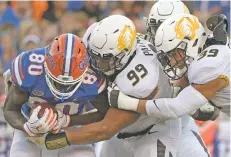  ?? ASSOCIATED PRESS ?? Florida tight end C’yontai Lewis, from left, is stopped for a loss by Missouri defensive linemen Walter Palmore and Chris Turner on Saturday in Gainesvill­e, Fla. No. 13 Florida was hammered, 38-17.