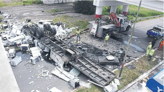  ?? Jorge granata/télam ?? Personal de Seguridad Vial remueve los electrodom­ésticos desparrama­dos y el remolque volcado en la ruta 33