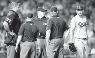  ?? Charles Rex Arbogast Associated Press ?? DODGERS PITCHER Clayton Kershaw stands by as the umpiring crew gathers after several lights went out in the sixth inning at Chicago’s Wrigley Field, causing a 10- minute delay.