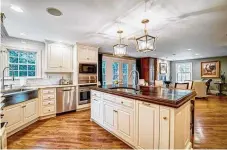  ?? ?? In the kitchen, an island with polished wood counter offers extended counter space for a breakfast bar and preparatio­n sink.