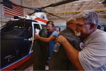  ?? Steve Gonzales / Houston Chronicle ?? Raymond Jacik and Michael Watkins, right, embrace the rescuers who saved them. They reunited Friday at Ellington Field.