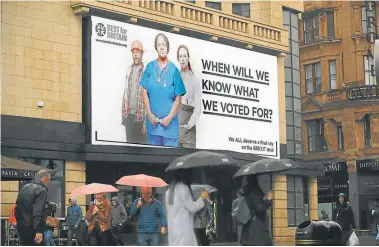  ?? AFP/CHRISTOPHE SIMON ?? Pedestrian­s walk under a new billboard launched by campaign group Best for Britain, in Leicester Square in London.