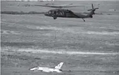  ??  ?? A military helicopter surveys the crash site near Colorado Springs in June. Michael Reaves, Denver Post file