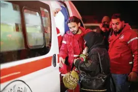  ?? SANA VIA AP ?? Syrian Arab Red Crescent members help a woman holding a baby get into an ambulance during an evacuation of nearly 30 critically ill people this week from eastern Ghouta, near Damascus, Syria. The evacuees were being taken to hospitals.
