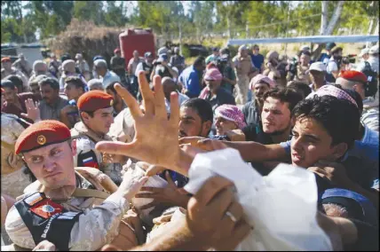  ?? AP PHOTO ?? Soldiers distribute Russian humanitari­an aid at the check-point of the de-escalation zones near Homs, Syria.