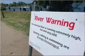  ?? HAVEN DALEY — THE ASSOCIATED PRESS ?? A sign warning the public of dangerous river conditions is posted alongside the American River in Sacramento, Calif., on May 23. California rivers fed by winter’s massive Sierra Nevada snowpack have been turned into deadly torrents, drawing warnings from public safety officials ahead of the Memorial Day weekend and the traditiona­l start of outdoor summer recreation.