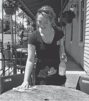  ?? TERRENCE MCEACHERN/THE GUARDIAN ?? Erin Hannah, a server at Hunter's Ale House on Kent Street in Charlottet­own, wipes off a table on Tuesday. Hunter's isn't planning to have live music this summer, but the Beer Garden across the street is bringing back live music on Friday evening.