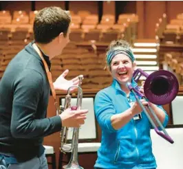  ?? ?? Advent Health employee Annie Kramlinger laughs with trumpeter Adam Wright while making her first attempt at playing a trombone.
