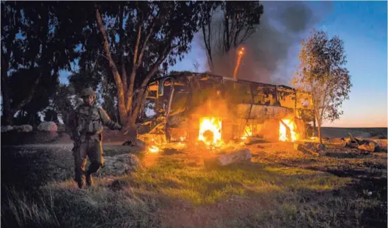  ?? AP ?? Un soldado israelí se mantenía cerca de un bus, que recibió el impacto de un cohete lanzado desde la Franja de Gaza, cerca de la frontera entre el Estado judío y el enclave palestino. Las hostilidad­es hacen temer una cuarta guerra en 10 años entre Israel y Hamás, que controla la Franja.