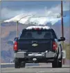  ?? Dan Watson/The Signal ?? A pickup truck with snow on its roof and bumper heads west on Newhall Ranch Road as snow can be seen on the distant hills Friday.
