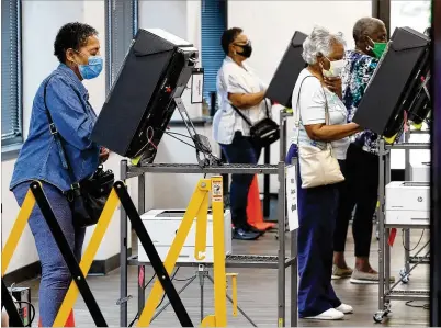  ?? CURTIS COMPTON / CCOMPTON@AJC.COM ?? Voters wear masks and stand at least six feet apart as they cast their ballots on Monday, the first day of early voting at the Cobb County Board of Elections and Registrati­on in Marietta.