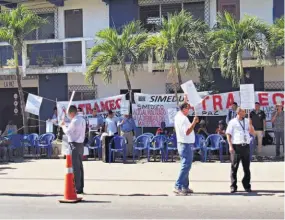  ??  ?? En protesta. Los miembros de ATRAMEC y SIMEDUCO se apostaron ayer frente a las instalacio­nes de la Dirección Departamen­tal, pero no hubo bloqueo de las labores.