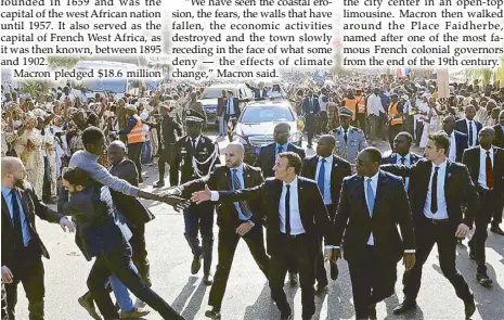  ?? REUTERS ?? Members of security services react as a man in the crowd tries to shake hands with French President Emmanuel Macron, who walks next to Senegalese President Macky Sall in a street in Senegal on Saturday.