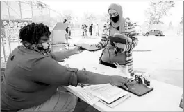  ?? JIM WILSON/THE NEW YORK TIMES ?? Velisa Woods, left, hands Chromebook­s to Faiza Ayesh on Monday, the first day of remote learning at an elementary school in Oakland, Calif. Ayesh has three children at the school.