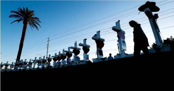  ?? ASSOCIATED PRESS PHOTOS ?? Manuela Barela on Friday passes crosses set up in honor of those who were killed during Sunday’s mass shooting in Las Vegas.