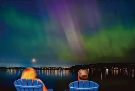  ?? Lindsey Wasson/Associated Press ?? People view the northern lights late Friday as they glow over Lake Washington, in Renton, Wash, due to a powerful solar storm.