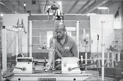  ?? Bloomberg News/TRAVIS DOVE ?? A systems operator works last month alongside robots that manufactur­e gears at the Southern German Electric Motor Works-Eurodrive Inc. factory in Lyman, S.C.