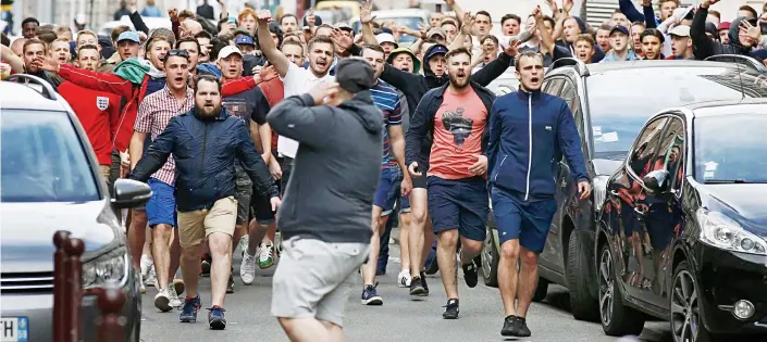  ??  ?? Trouble ahead: A large group of chanting England fans surging through the centre of Lille yesterday, before they were herded into a side street by the police