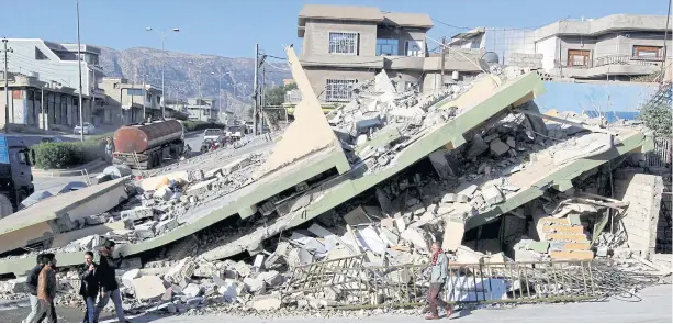  ?? AFP ?? ABOVE A collapsed building is seen in the town of Darbandikh­an, Iraq, after yesterday’s temblor.