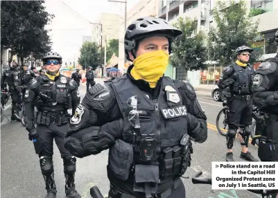  ??  ?? > Police stand on a road in the Capitol Hill Organized Protest zone on July 1 in Seattle, US
