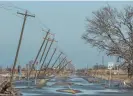  ?? Photograph: Tannen Maury/EPA ?? Utility poles lean along a flooded road in Cameron, Louisiana, in October 2020.