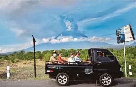  ?? AGENCY PIX ?? People riding on an open car as Mount Agung spews smoke in Karangasem, Bali, yesterday.