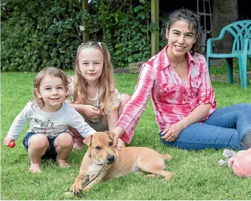  ?? VALENTINA BELLOMO/STUFF ?? Gracelyn Ball, 2, Elise Ball, 6, and Olivia Ball playing with foster puppy Candy, one of a number of dogs rescued in recent months.