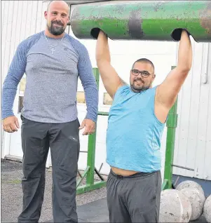  ?? ERIC MCCARTHY/JOURNAL PIONEER ?? Event organizer and defending champion Alex Wallace stands on a 600-oound tire for a closer look as training partner Mitch Illsley tries out the log press in advance of the Prince County Exhibition’s Strongest Man in P.E.I competitio­n.