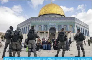  ?? ?? JERUSALEM: Zionist policemen stand guard in front of Muslim women praying in front of the Dome of the Rock mosque as a group of religious Jewish men and women visit the Temple Mount, which is known to Muslims as the Haram Al-Sharif (The Noble Sanctuary), at the Al-Aqasa mosques compound in the old city of Jerusalem on April 20, 2022. — AFP