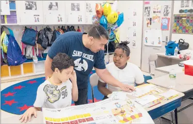  ?? PATRICK RAYCRAFT/HARTFORD COURANT ?? “I felt validated. It’s been a long road as far as growing up in the city, one of six kids, single [parent] family. I think that that does help me as a teacher,” says SAND School fourth-grade teacher Narciso Moquete about being named the 2018-19 Hartford Public Schools teacher of the year on Thursday evening. Moquete helps students Daniel Lopez, 10, left, and Shaheim Wilson, 10, with an English Language Arts project on Friday morning.