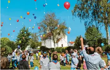  ?? Fotos: Silke Federsel ?? Pfadfinder und Kinder haben anlässlich des 150. Jubiläums der evangelisc­hen Kirche Ludwigsmoo­s bunte Luftballon­s steigen las sen.