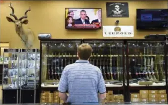  ?? MiCHAel HolAHAN — AUGUStA CHRoNiCle ViA AP ?? Brett Busbee, sales associate at Southeaste­rn Armory, a gun store in Augusta, Ga., watches as President obama speaks at the White House about his gun control measures tuesday. President obama unveiled his plan tuesday to tighten control and enforcemen­t...