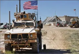  ?? HUSSEIN MALLA / AP ?? A U.S. soldier (left) sits on an armored vehicle Wednesday behind a sand barrier at a newly installed position near the tense front line between the U.S-backed Syrian Manbij Military Council and Turkish-backed fighters in Manbij, northern Syria.