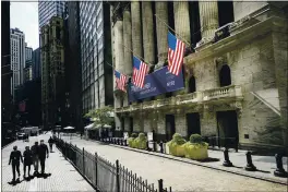  ?? JOHN MINCHILLO — THE ASSOCIATED PRESS ?? Pedestrian­s pass the New York Stock Exchange.