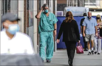  ?? JOHN SPINK / JSPINK@AJC.COM ?? Dr. Chris Sadlack (center) walks outside Grady Hospital on Thursday. Grady and other local hospitals are seeing a surge in new patients just weeks after Channel 2 Action News reported hospitaliz­ations were way down. Nearly 510 ICU beds are open across the state, or about 18% of the total, according to Georgia Emergency Management and Homeland Security Agency data.