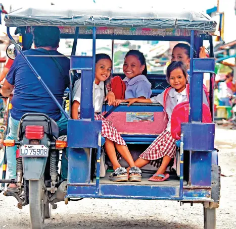  ?? MARK PERANDOS ?? OFF TO CLASS. Schoolgirl­s smile while onboard a tricycle going to Quezon Elementary School along Ponce Street, Davao City.