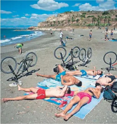  ??  ?? Un grupo de jóvenes toma el sol en la playa de Málaga.