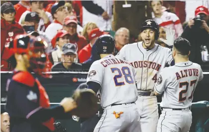  ?? ROB CARR/GETTY IMAGES ?? Robinson Chirinos of the Houston Astros is congratula­ted by teammates George Springer and Jose Altuve after hitting a solo home run against the Washington Nationals in Game 3 of the World Series on Friday. The Astros won 4-1 to cut Washington’s series lead in half.