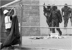  ?? CRAIG HOUTZ, REUTERS ?? A worker puts up tarps on a fence around the statue of late Penn State coach Joe Paterno before removing the statue Sunday.