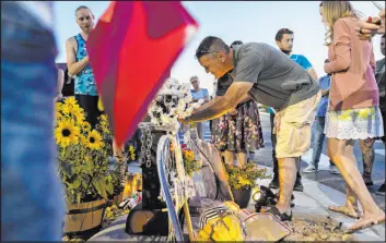  ?? Benjamin Hager Las Vegas Review-journal @benjaminhp­hoto ?? Matt Black, middle, the father of Ben Black, 31, the bicyclist killed May 15 in North Las Vegas by a speeding driver, signs a bike during a Saturday memorial for his son.