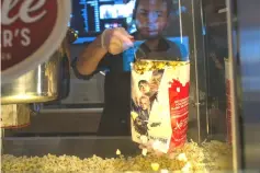  ??  ?? A worker scoops popcorn at a concession stand inside a Cinemark movie theatre in Los Angeles on Oct 31, 2017. (Below) Vehicles pass the Landmark Century Centre Cinema in Chicago on Aug 16, 2018. (Left) Customers wait to buy concession­s at the Regal Cinemas L.A. LIVE Stadium 14 movie theatre in Los Angeles on Apr 21, 2017. — WP-Bloomberg file photos