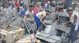  ?? ARVIND YADAV/HT ?? People sift through their gutted properties at Malviya Nagar on Sunday.